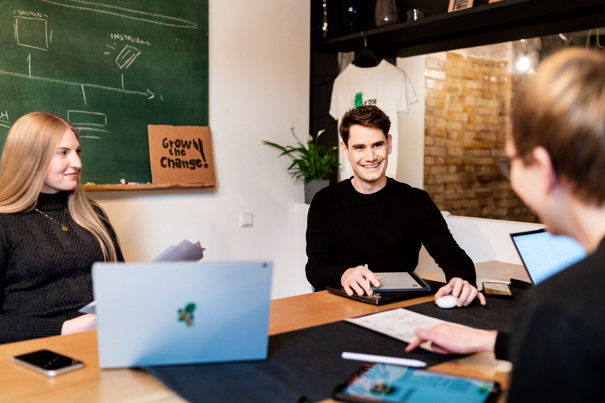 urbanhive team in einer Besprechung mit grow the change logo im Hintergrund